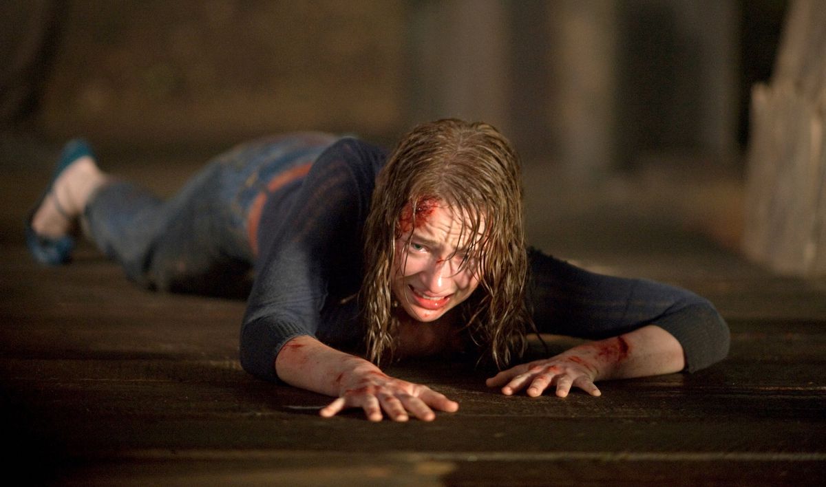 Dana (Kristen Connolly) striscia lungo un molo di legno, bagnata, insanguinata e terrorizzata, in The Cabin in the Woods del 2011