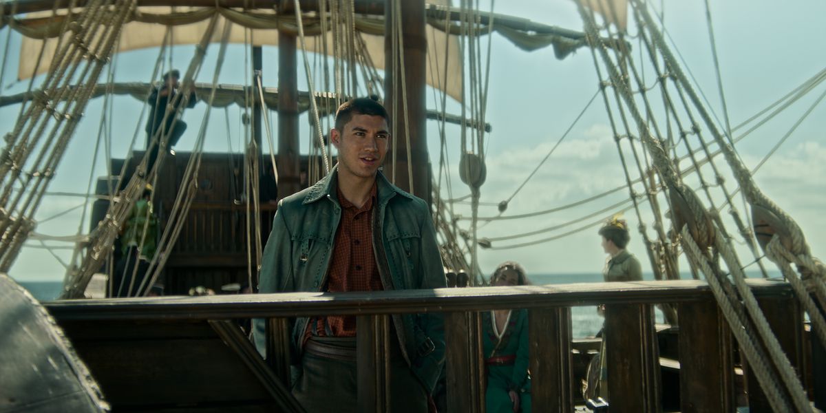 Archie Renaux nei panni di Malyen Oretsev si trova ai binari della nave di Nikolai guardando verso il mare nella stagione 2 di Shadow and Bone.