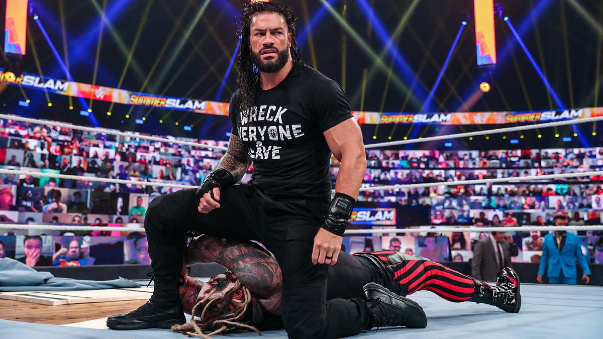Roman Reigns si inginocchia sul suo avversario mentre è circondato da schermi in WWE SummerSlam 2020