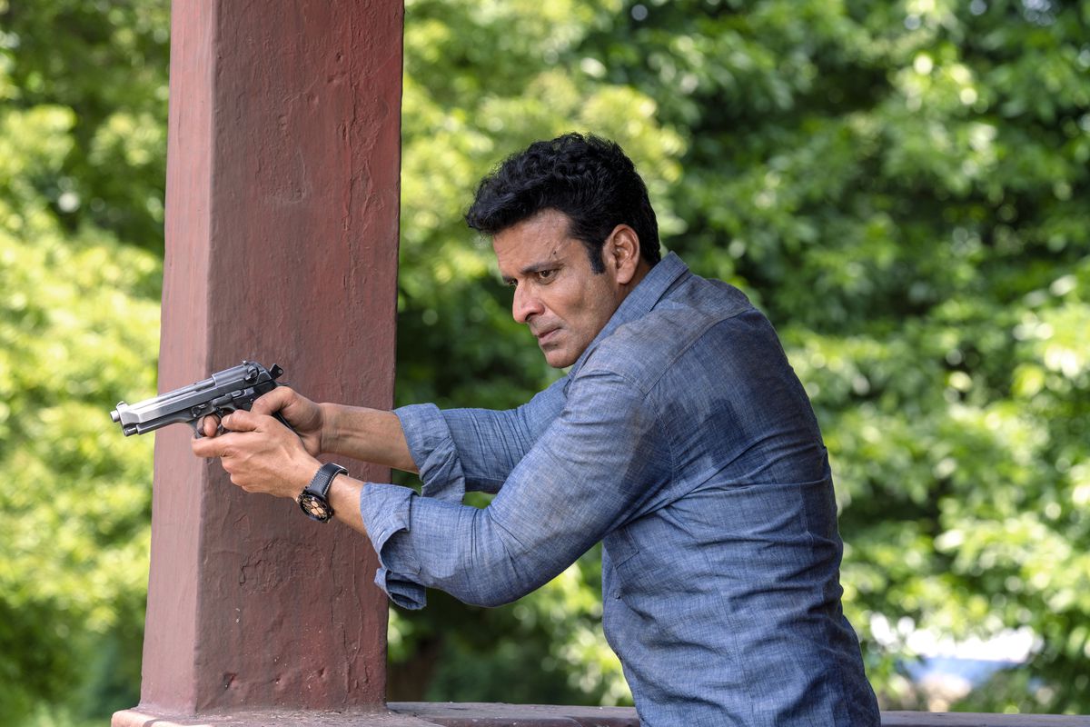 Manoj Bajpayee impugna una pistola mentre indossa una maglietta azzurra in The Family Man.