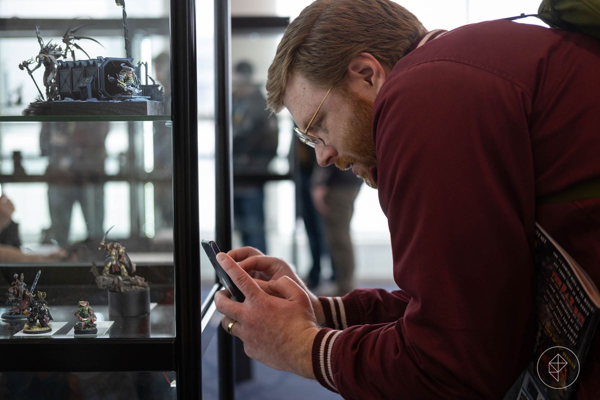 A red-haired man with a cell phone takes pictures of the miniatures on display at the Golden Demon.