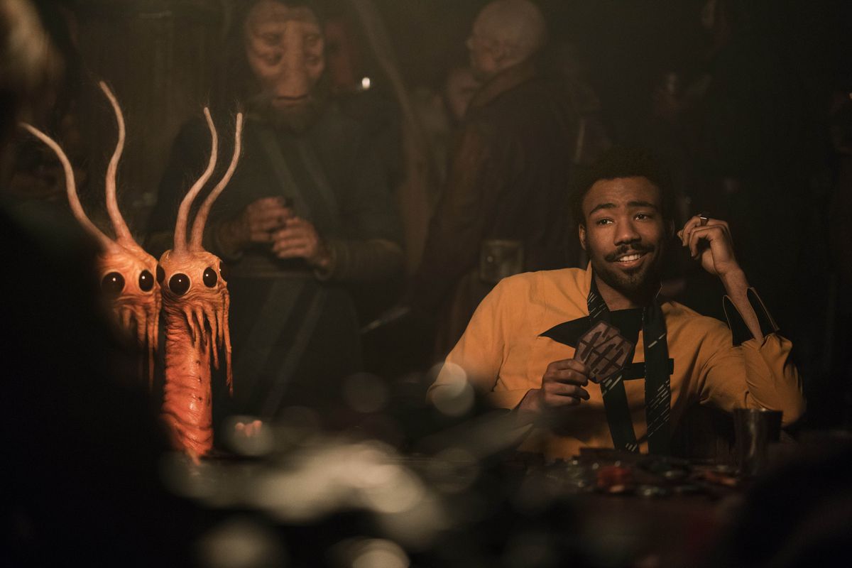 Donald Glover nei panni di Lando Calrissian in Solo: una storia di Star Wars.  Si rilassa viscido a un tavolo da gioco sabacc, circondato da strani alieni. 
