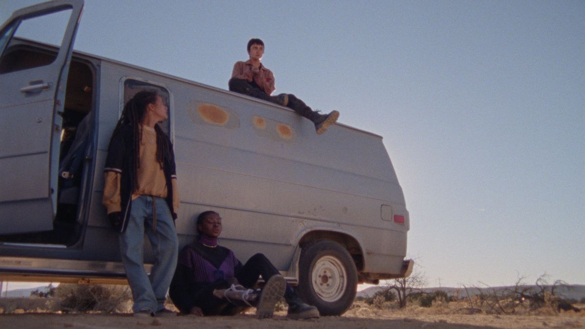 I giovani di How to Blow Up a Pipeline si siedono sopra e davanti a un furgone bianco.  Ci si appoggia contro.  Lo sfondo è il desolato deserto del Texas occidentale.