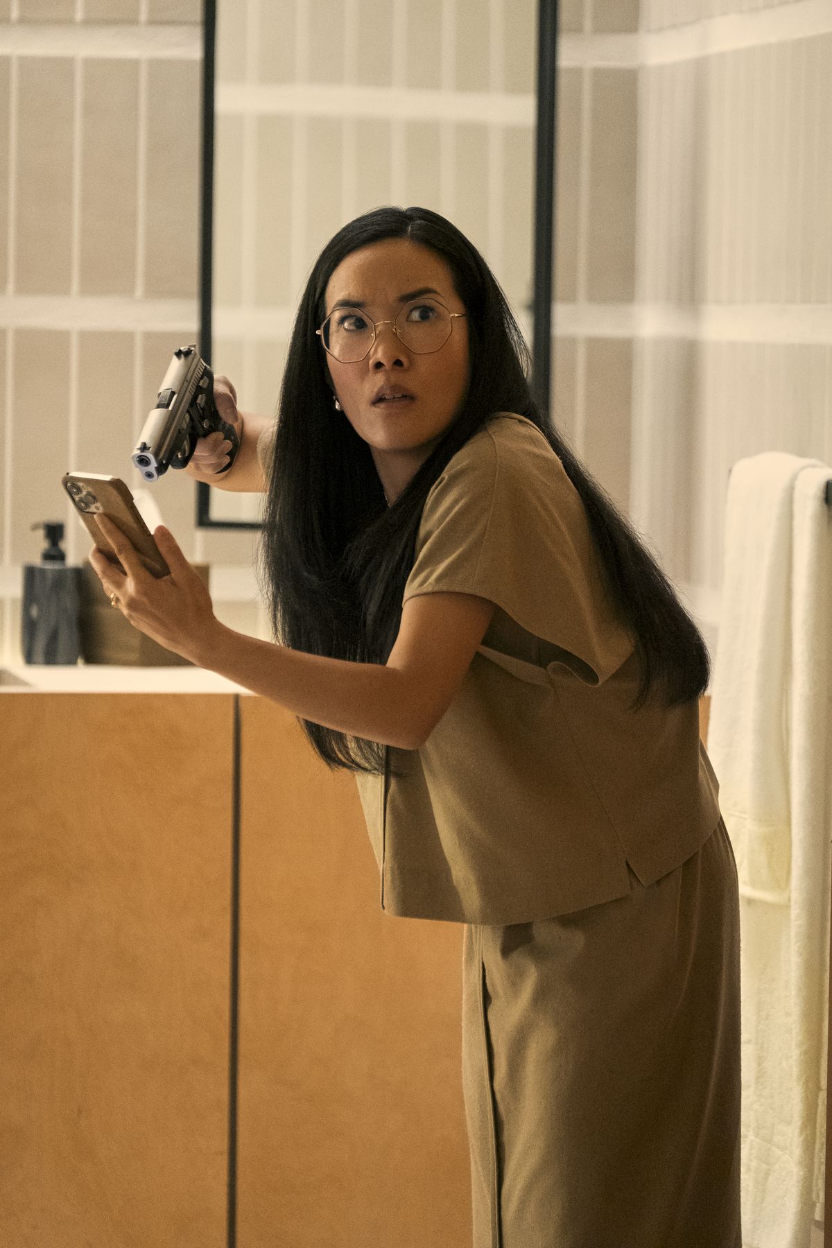 Amy (Ali Wong) tiene in mano una pistola contro un telefono e guarda scioccata qualcosa fuori dalla telecamera