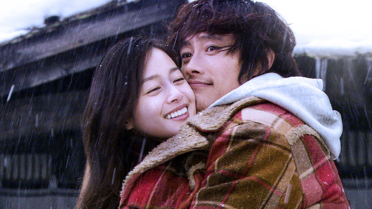Lee Byung-hun e Kim Tae-hee si abbracciano nella neve sotto un cappotto condiviso in Iris.