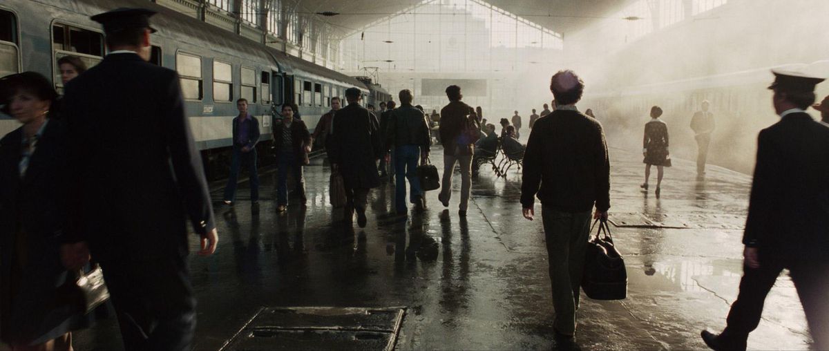 I passeggeri che trasportano valigie camminano accanto a un treno in una stazione illuminata dalle luci dei finestrini spenti, che proiettano ogni persona in silhouette a Monaco 