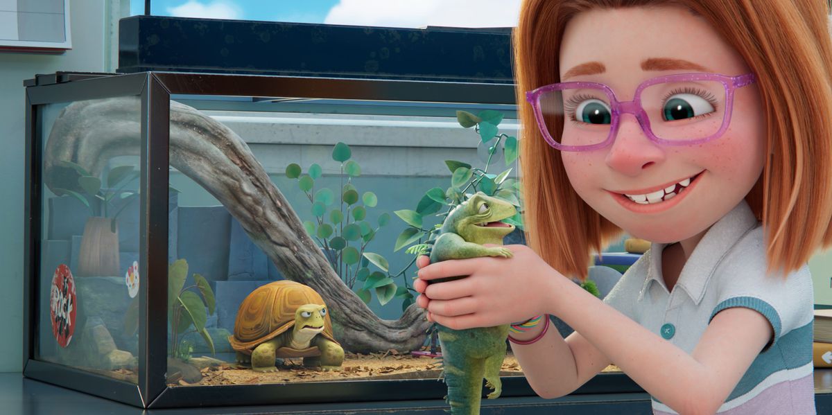 Una sorridente ragazza dai capelli rossi con gli occhiali rosa tiene in mano un'iguana sorridente mentre una tartaruga in un acquario dietro di loro li fissa entrambi in Leo di Netflix