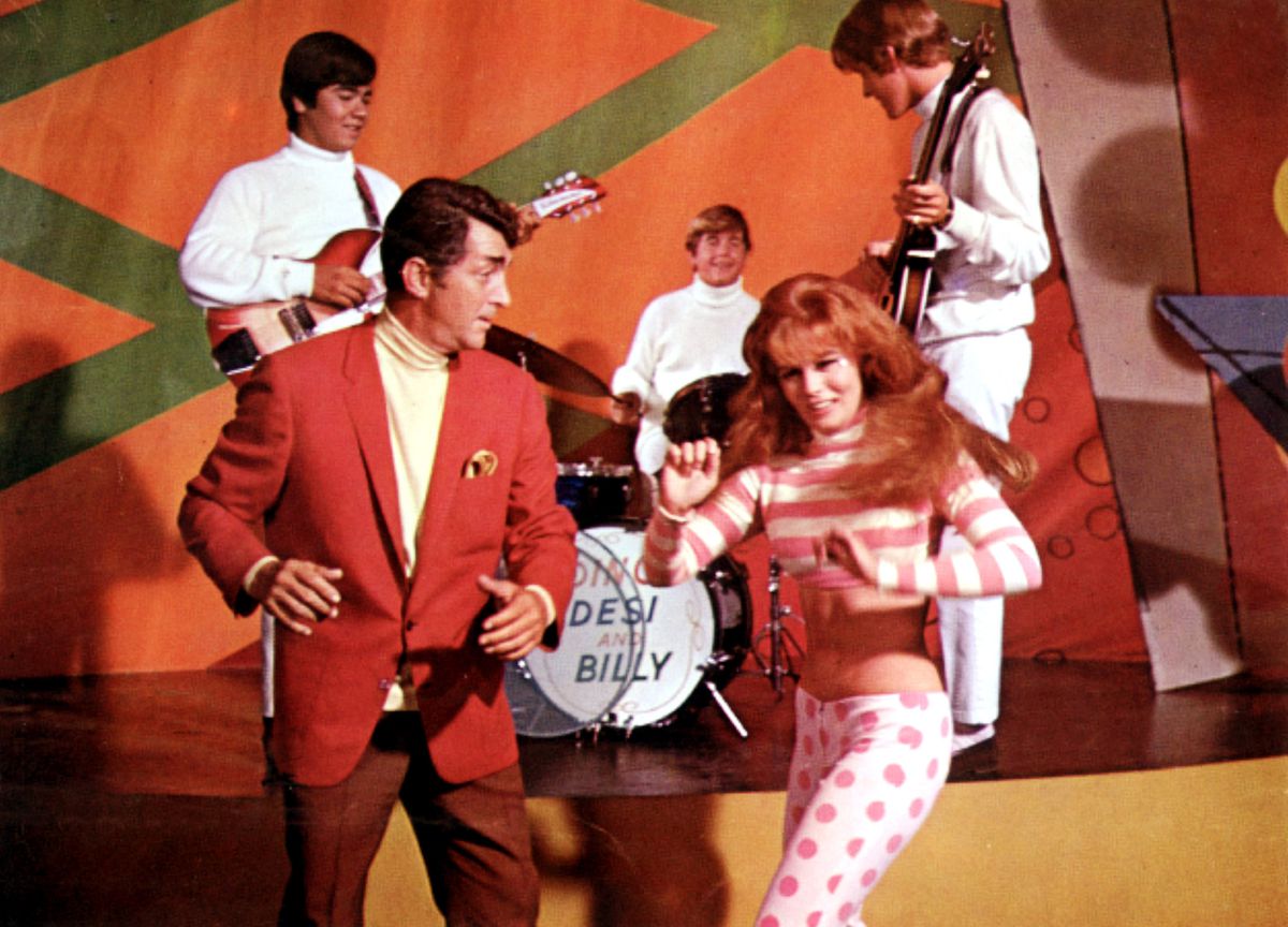 Matt Helm in abito rosso balla con una ragazza dai capelli rossi davanti alla band Desi e Billy