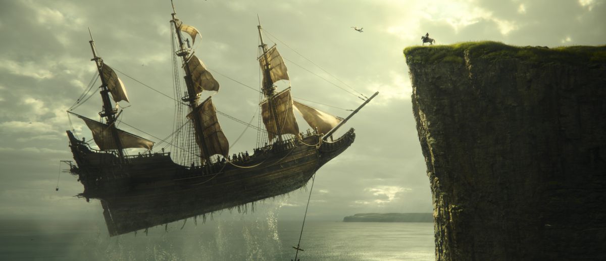 Una nave volante con le vele si libra sull'acqua e si avvicina a una scogliera, dove una figura siede su un cavallo in Peter Pan e Wendy.
