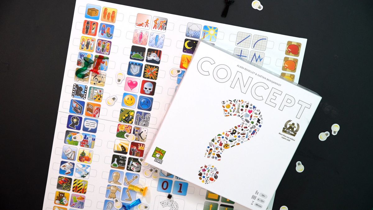 La scatola del gioco da tavolo per Concept si trova in cima al suo colorato tabellone di icone con piccoli pezzi di gioco e gettoni segnapunti sparsi sul tavolo.