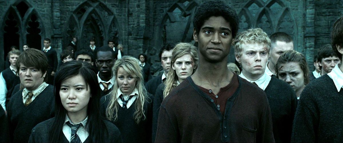 Cho Chang (Katie Leung), Dean Thomas (Alfred Enoch) e una folla di altri studenti di Hogwarts stanno davanti alla scuola, malconci e insanguinati, in Harry Potter e i Doni della Morte: Parte 2.
