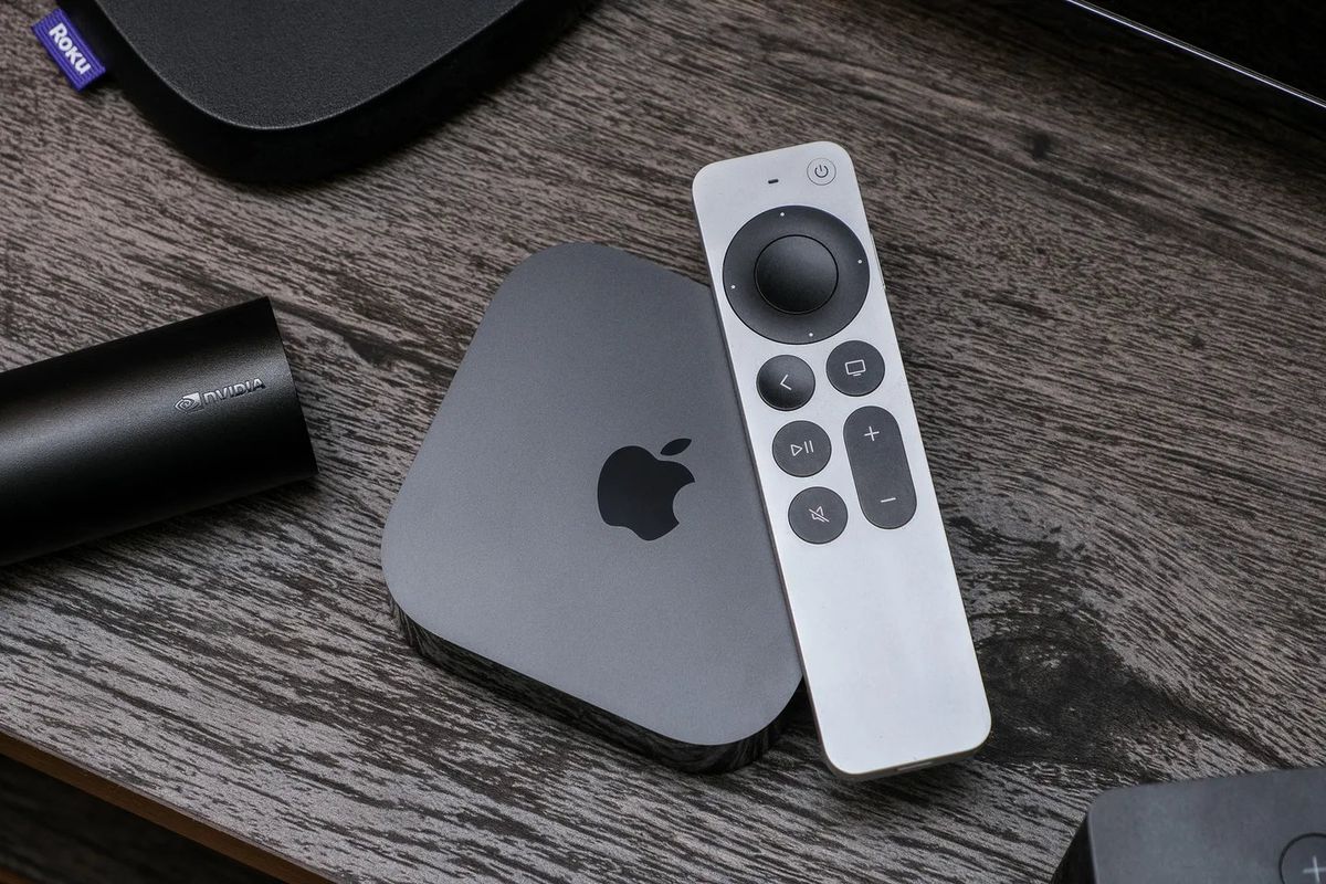 L'Apple TV 4K seduta su un centro di intrattenimento in legno.  Il telecomando Siri è sopra di esso.