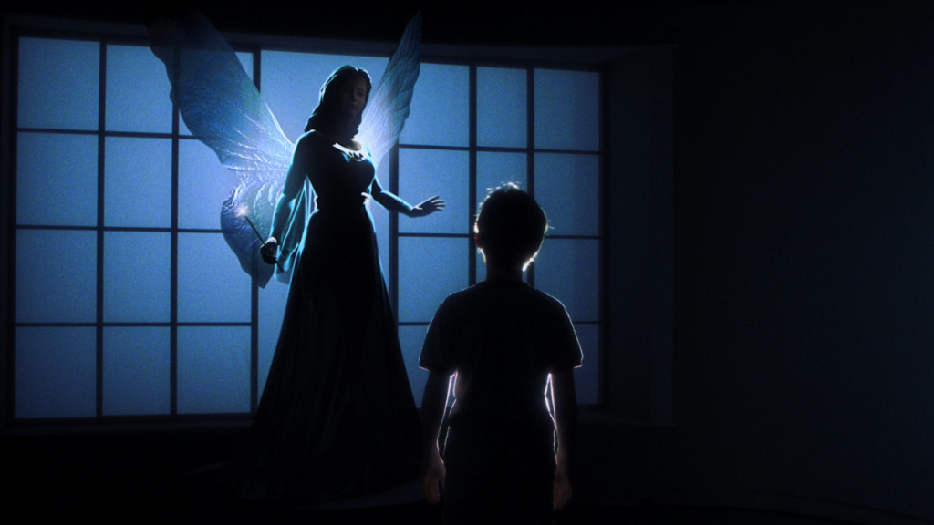 Un giovane è protagonista di una donna in un maestoso abito blu con ali di fata che tiene in mano una bacchetta in una stanza buia.