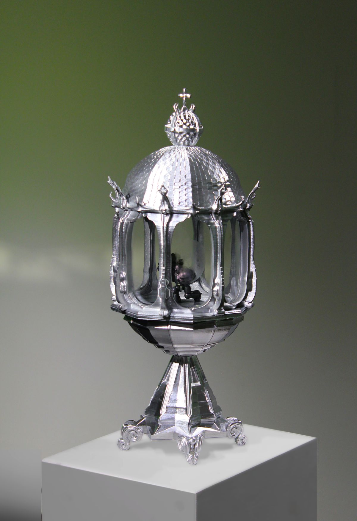 Un reliquiario d'argento decorato contenente una statuina di Space Marine di Warhammer 40.000 in posizione inginocchiata