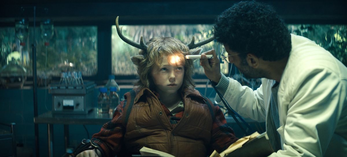 Il dottor Singh (Adeel Akhtar) punta una torcia a Gus (Christian Convery), un ragazzino apprensivo con le corna e le orecchie di un cervo in Sweet Tooth.