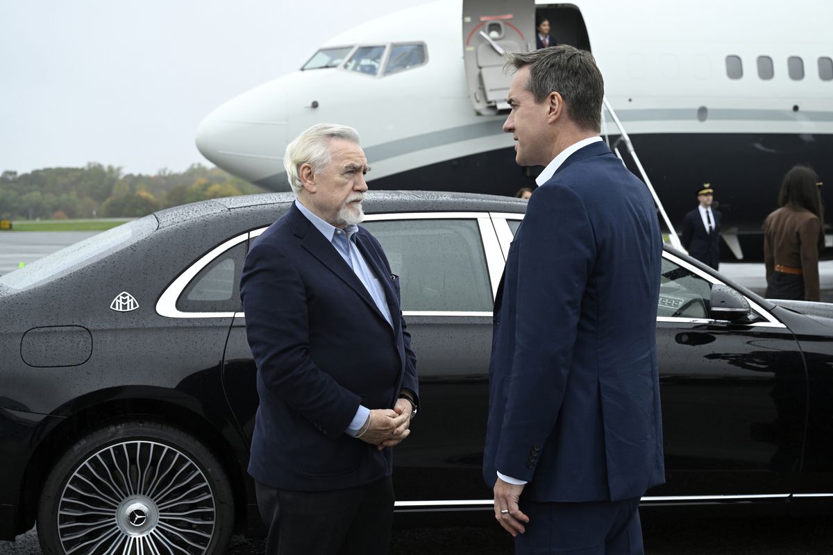Logan Roy e Tom Wambsgams parlano davanti a un'auto nera parcheggiata davanti a un jet privato in attesa nella quarta stagione di Succession della HBO.