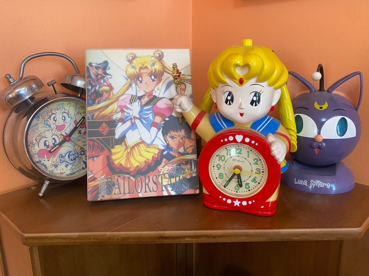 Una serie di oggetti a tema Sailor Moon, tra cui un orologio e un cofanetto DvD.