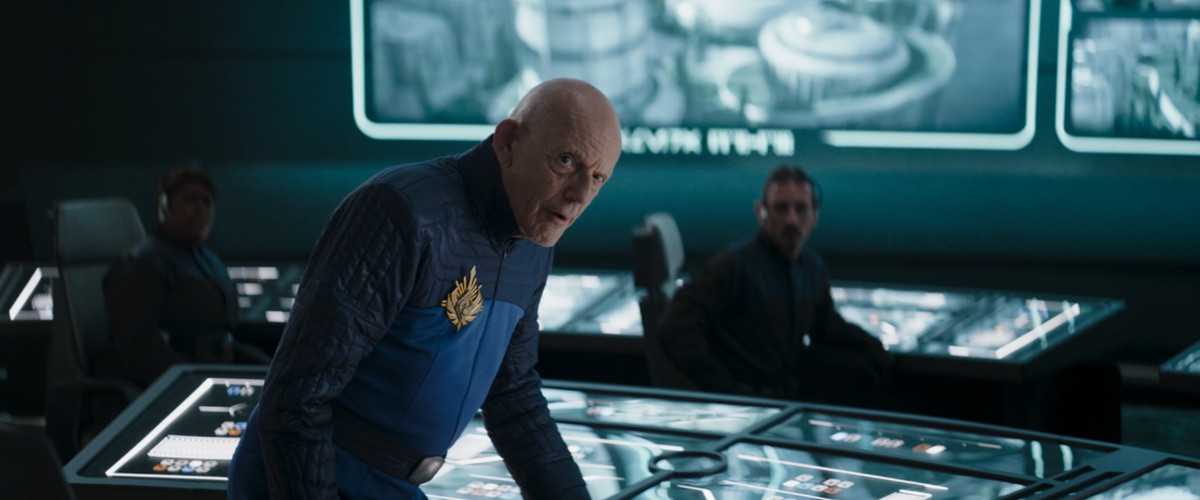 Christopher Lloyd in The Mandalorian indossa un'uniforme di sicurezza Plazir-15 e si china su una consolle di bottoni 