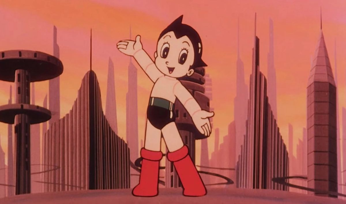 Uno screenshot a colori del cartone animato Astro Boy del 1980, con Astro Boy in piedi su una sporgenza che domina una città futuristica.