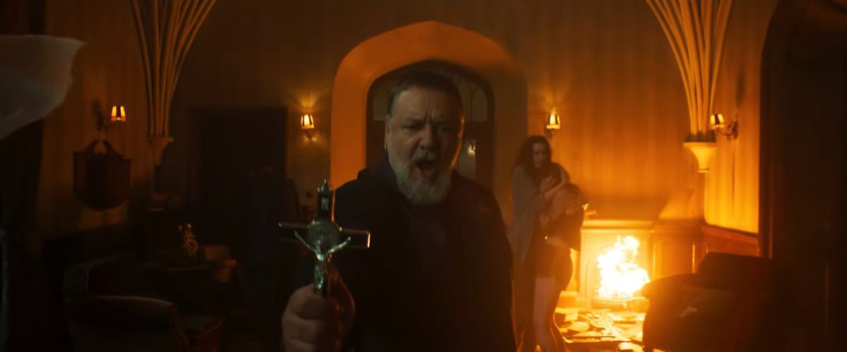 Russell Crowe tiene una croce con le fiamme dietro di lui in The Pope's Exorcist.
