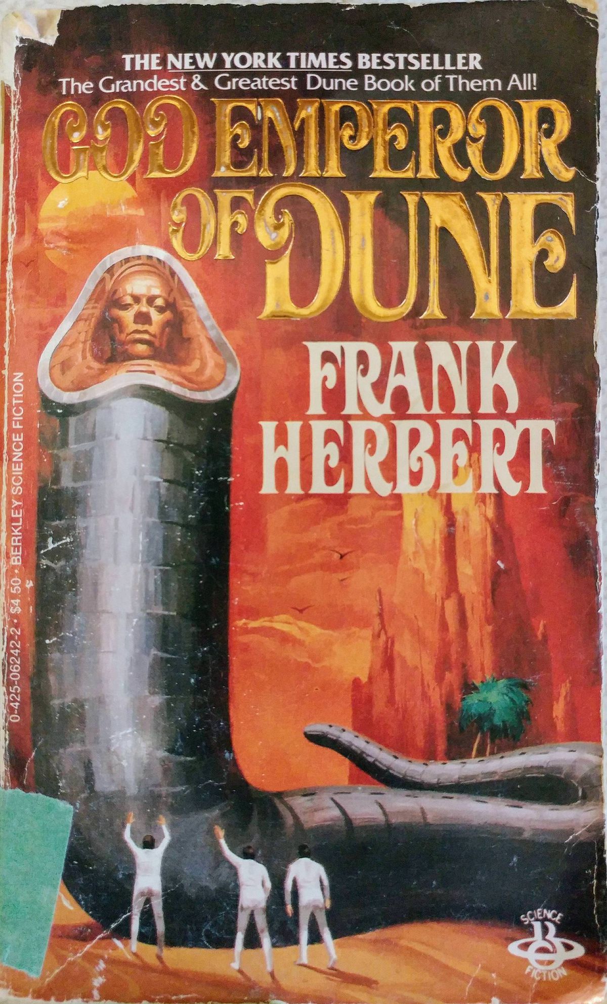 La copertina di Berkley Books del 1984 di God Emperor of Dune , con tre uomini vestiti di bianco in piedi alla base di un'imponente figura a forma di verme grigia e squamosa con un volto umano al posto della bocca
