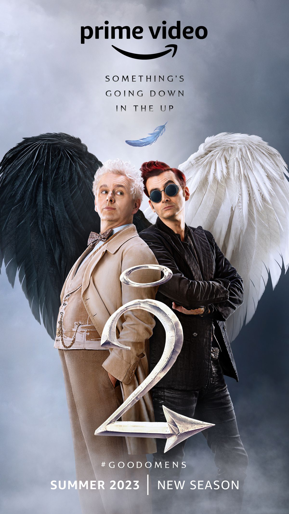 Un poster per la seconda stagione di Good Omens, con Michael Sheen nei panni di Aziraphale e David Tennant nei panni di Crowley, in piedi schiena contro schiena con le ali che formano un cuore. 