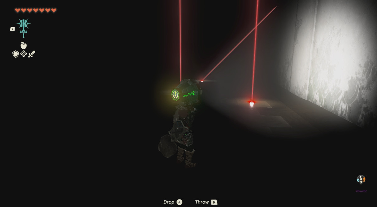Link punta una torcia sui laser rossi.  La stanza è completamente buia.