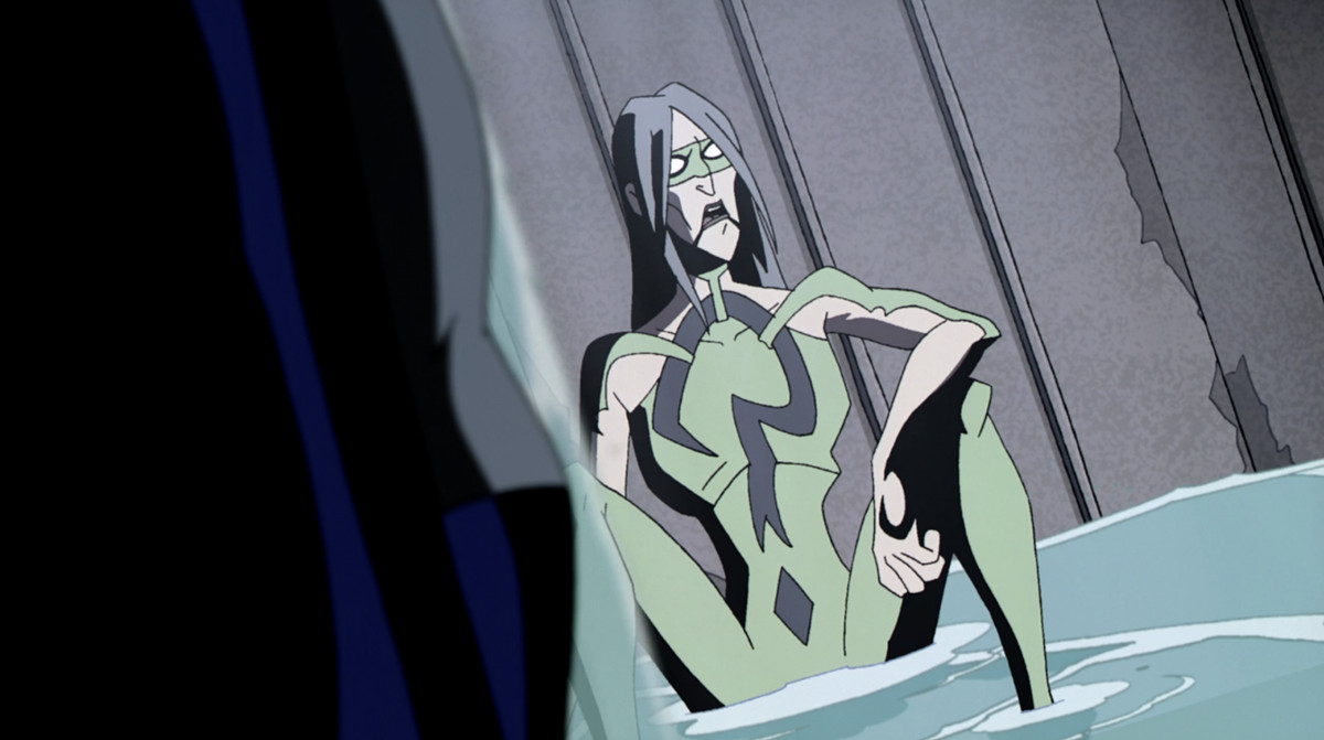 L'Enigmista, seduto per terra con indosso un abito verde attillato con un punto interrogativo e una maschera
