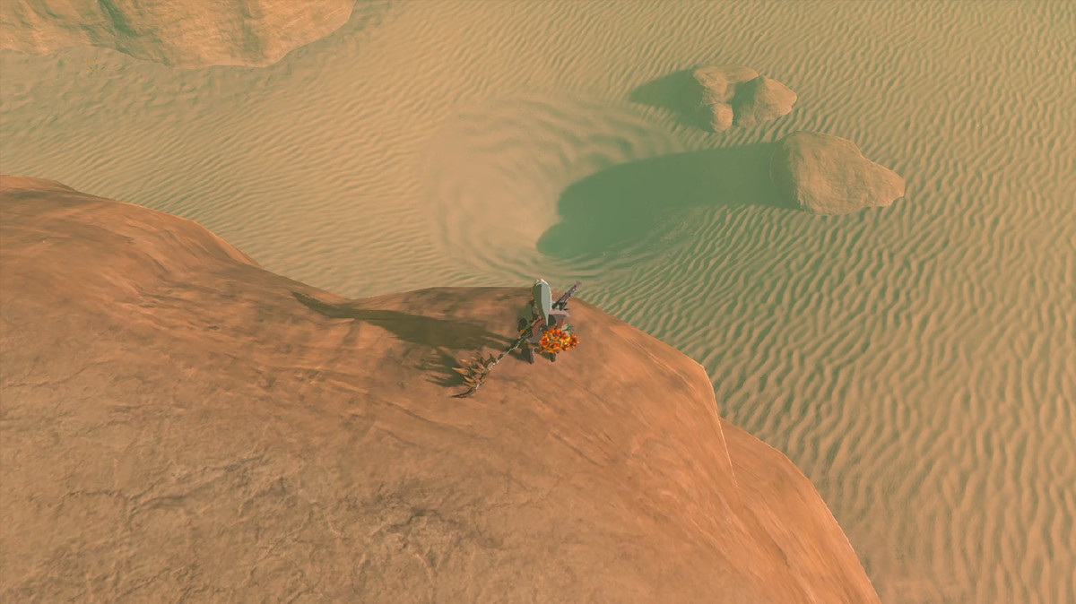 Link si trova su una scogliera rocciosa in un deserto - sotto di lui c'è un vortice di sabbie mobili