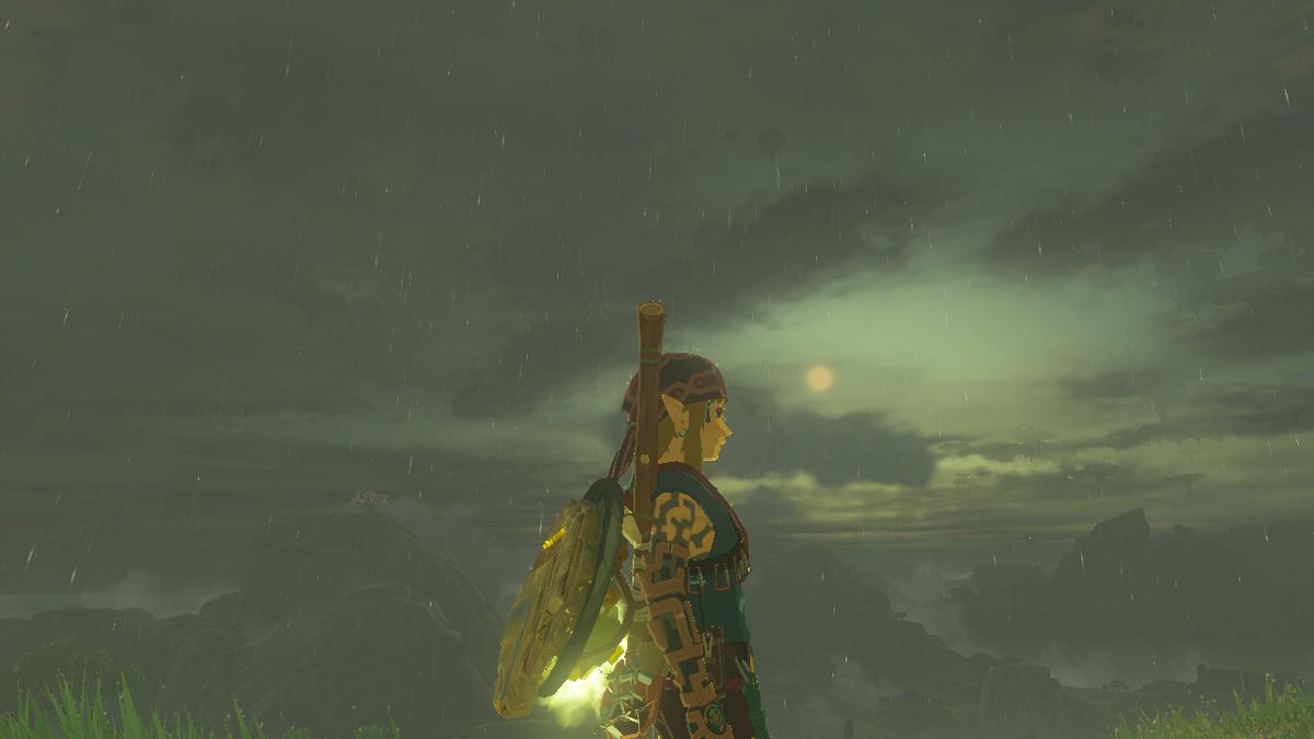 Link si trova di lato durante una serata piovosa con il sole in lontananza indossando l'armatura da arrampicata in Zelda: Tears of the Kingdom