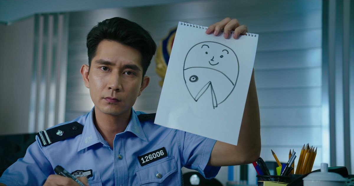 Sheung-ching Lee, che indossa un'uniforme blu della polizia, tiene in mano un esilarante disegno di una sirena 