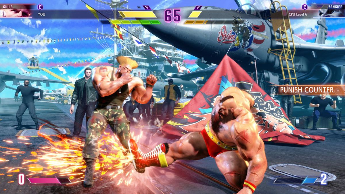 Zangief prende a calci Guile su un palco ambientato su una portaerei in uno screenshot di Street Fighter 6