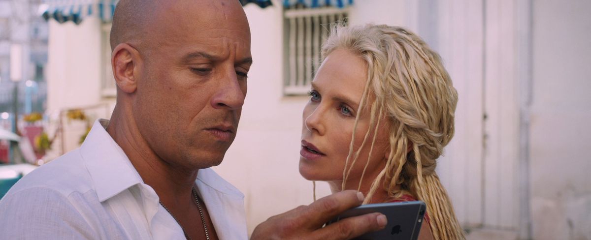 Dom Toretto (Vin Diesel) guarda un telefono mentre Cipher (Charlize Theron) guarda in F8: The Fate of the Furious