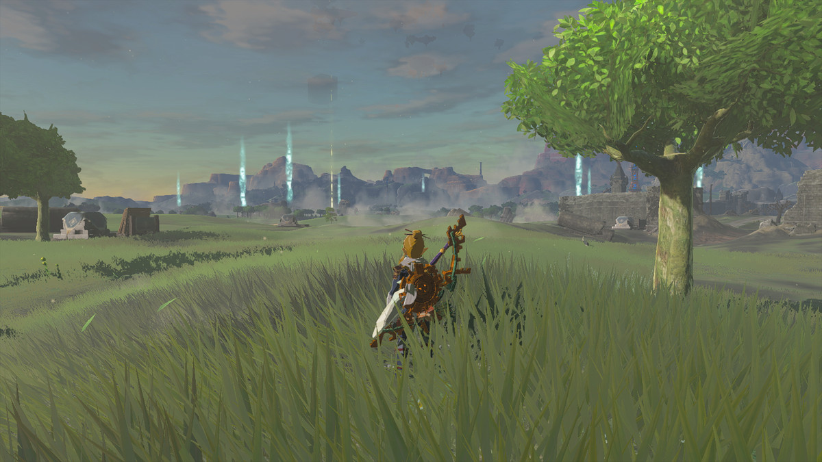 Un'immagine di Link in piedi in un campo in The Legend of Zelda: Tears of the Kingdom.  Lontane colonne di luce segnano gli ingressi alle grotte. 