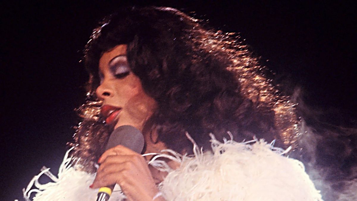 Un'immagine d'archivio di Donna Summer in un boa di piume bianche con un microfono in mano.