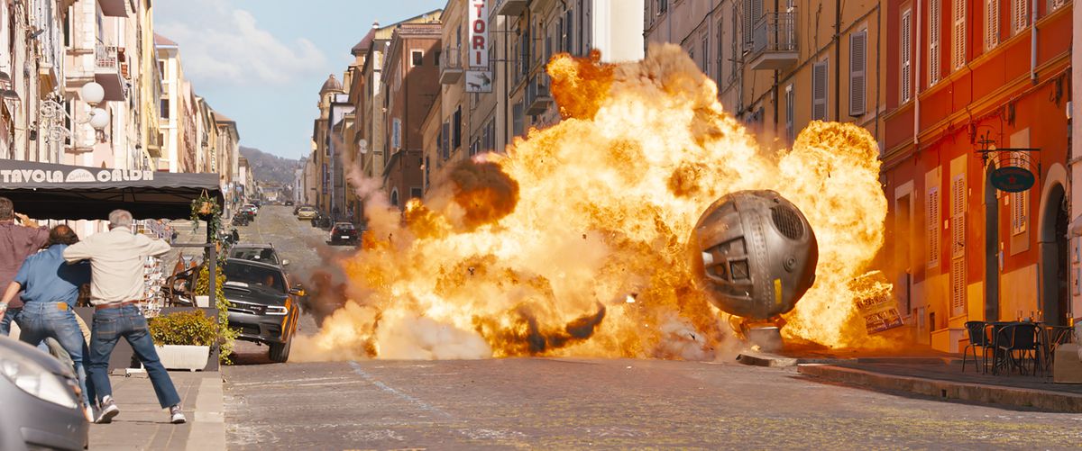 Una gigantesca bomba metallica sferica fiammeggiante rotola per le strade di Roma, fracassando veicoli, in una scena d'azione di Fast X
