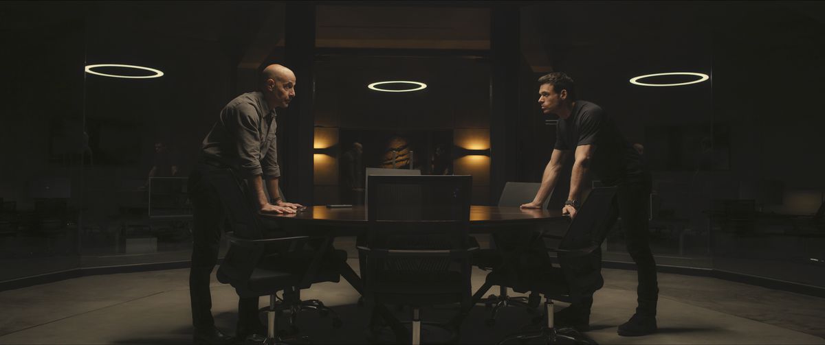 Bernard (Stanley Tucci) e Mason (Richard Madden) si chinano alle estremità opposte di un tavolo e si guardano l'un l'altro in un fotogramma della stagione 1 di Citadel