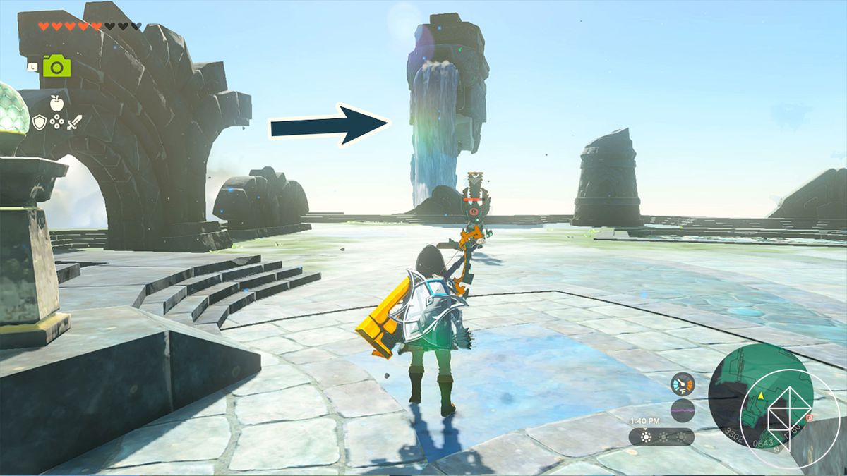 Link si trova su un pianerottolo decorativo in pietra e, di fronte a lui, un pilastro di pietra con una cascata bloccata dal fango.  Una freccia in sovrimpressione indica la cascata, indicando che è quello che Link deve ripulire.