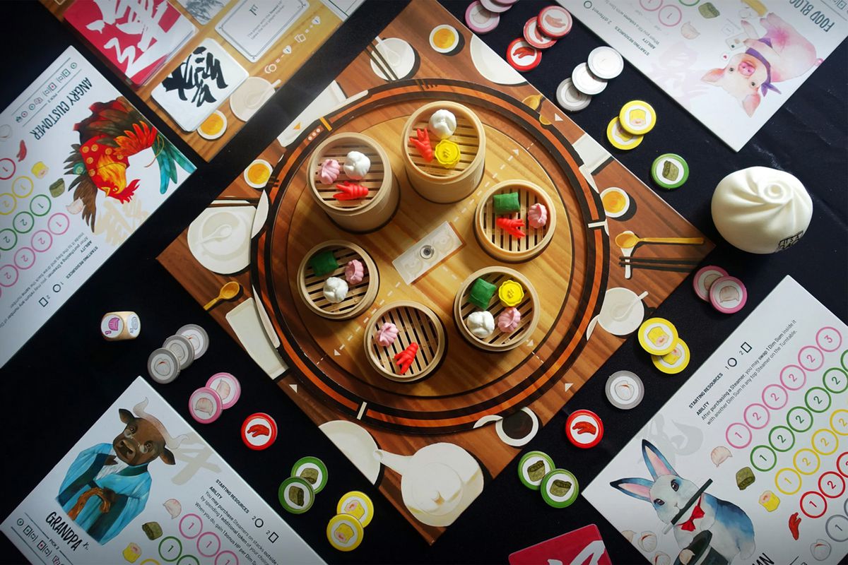 Una vista dall'alto di Steam Up, che mostra le carte dei personaggi del giocatore - modellate sullo zodiaco cinese - e i minuscoli alimenti morbidi su un tabellone centrale rotante.