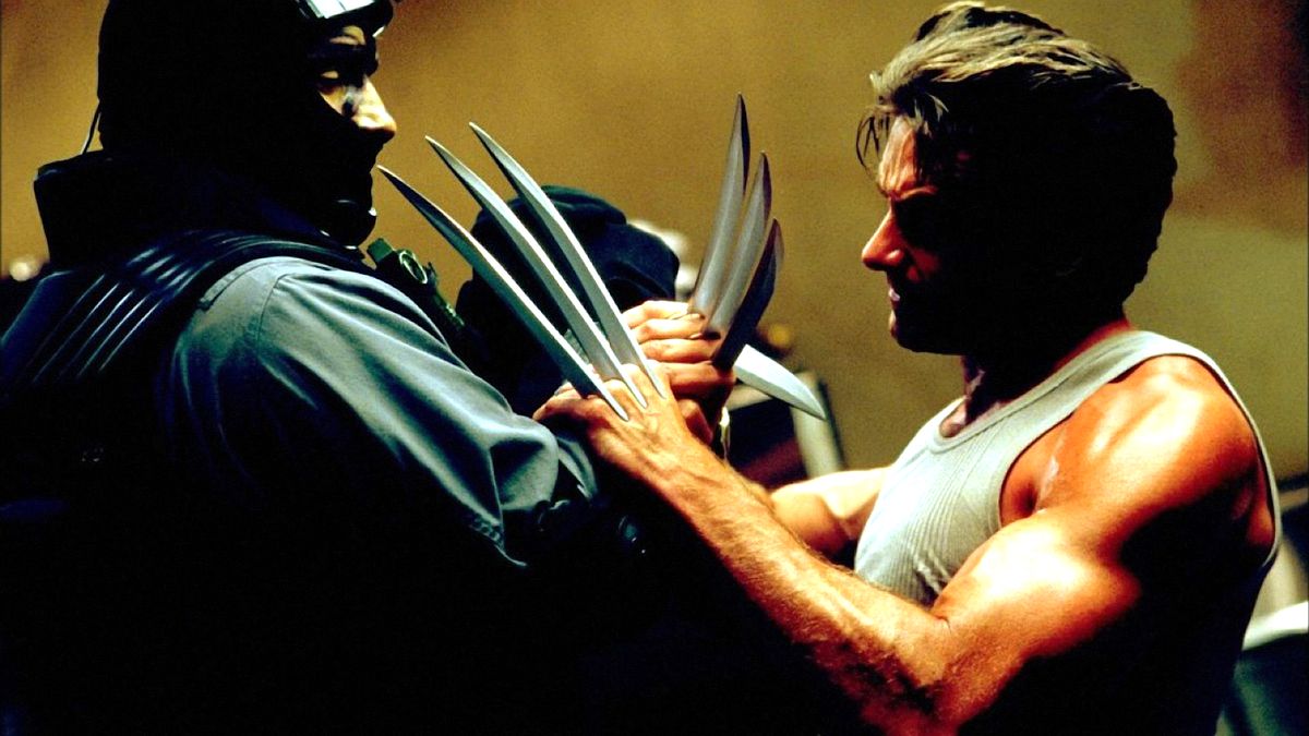 Hugh Jackman nei panni di Wolverine in X2: X-Men United mette i suoi artigli di adamantio in faccia a un mook dalla maschera nera 