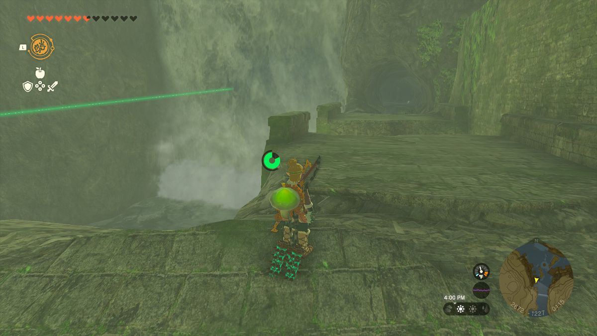 Link guardando l'ingresso di una grotta che conduce dietro una cascata.  Un raggio verde punta verso di esso.