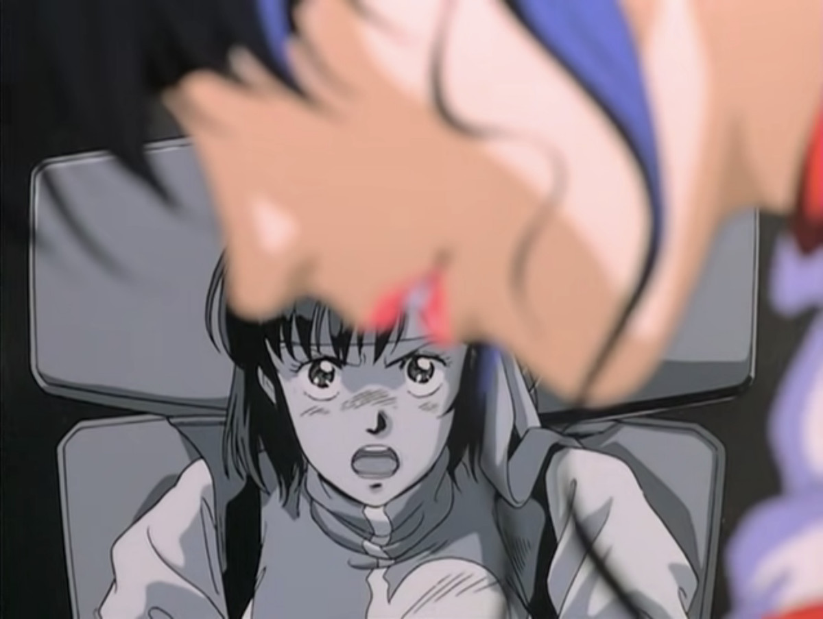 Noriko sullo sfondo in bianco e nero che guarda Kazumi, sfocata e piangente in primo piano, e urla in un fotogramma di Gunbuster