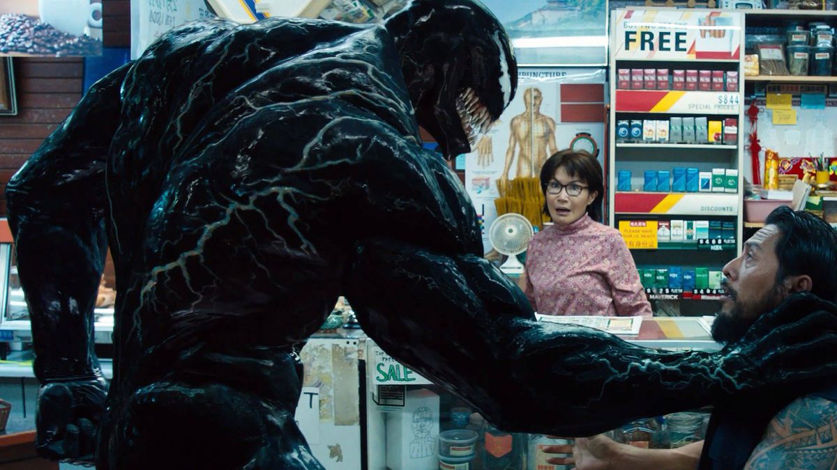 (LR) Venom (Tom Hardy) minaccia un ladro davanti alla signora Chen (Peggy Lu) in Venom.