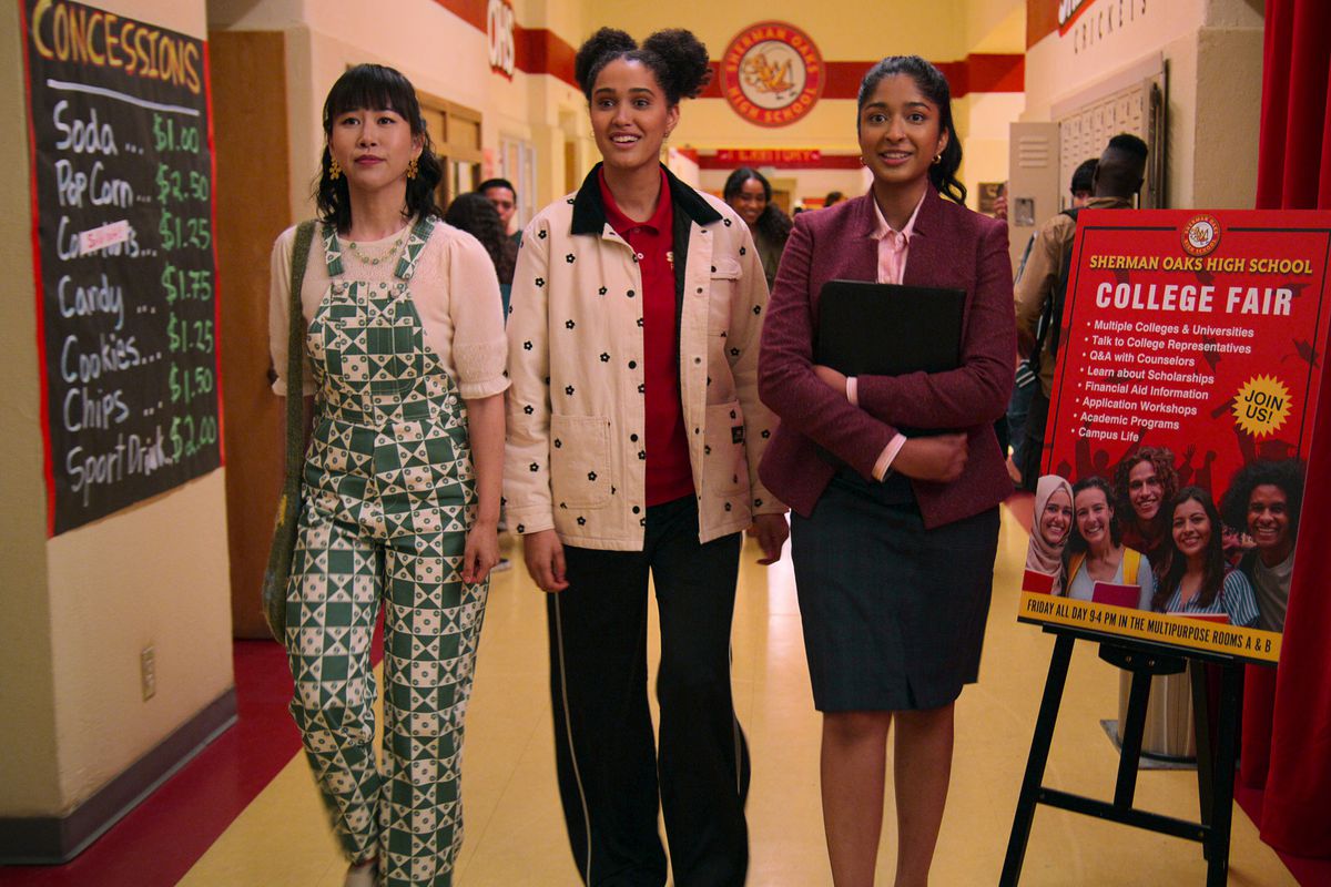 Eleanor, Fabiola e Devi nel corridoio del liceo, vestite per una fiera universitaria. 