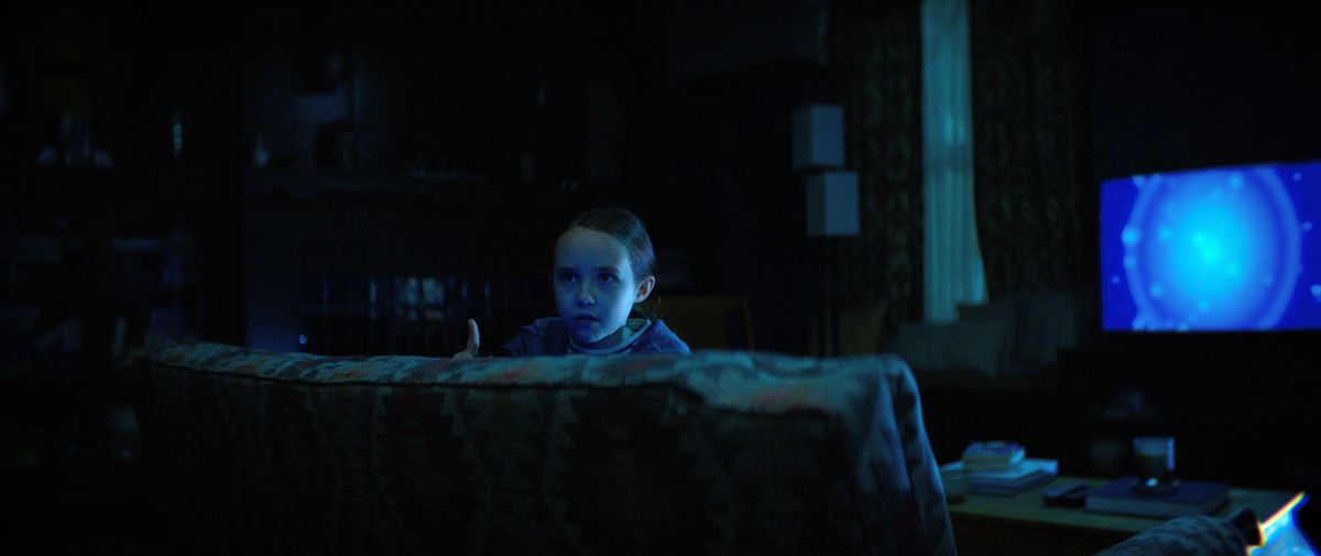 Sawyer (Vivien Lyra Blair) fa capolino dal divano mentre la TV blu brilla dietro di lei in The Boogeyman