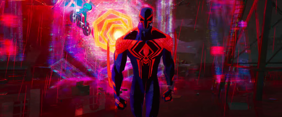 Spider-Man 2099 cammina verso la telecamera con un wormhole dai colori vivaci di rossi, rosa, gialli e blu che vortica dietro di lui in Spider-Man: Across the Spider-Verse